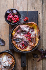 Pannukakku or Danish pancake with berries topping covered with sugar powder