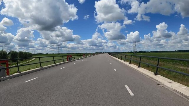POV Driving along river IJssel with polder landscape, floodplains and beautiful clouds