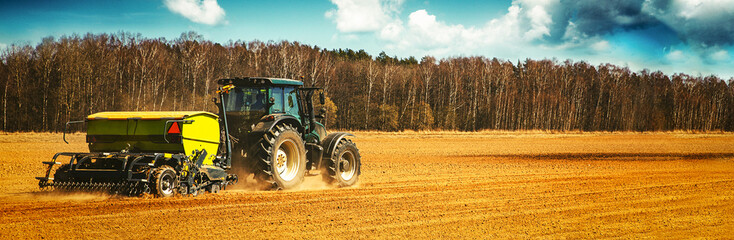 farmer with tractor seeding - sowing crops on agricultural field in spring. banner copy space