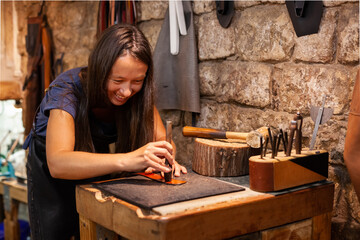 Female leather artisan creating a hand-made belt in a traditional workshop