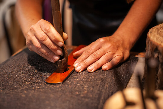 Hands of female leather artisan creating a hand-made belt