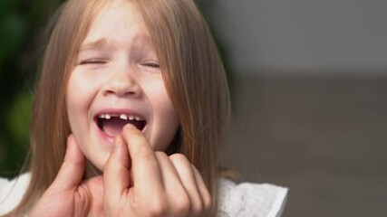dad's hand wobbles baby tooth of little daughter.