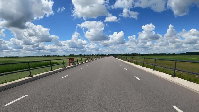 POV Driving along river IJssel with polder landscape, floodplains and beautiful clouds
