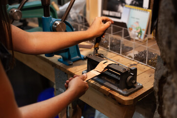 Hands of female leather artisan creating a hand-made belt