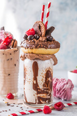 Chocolate indulgent frosting exreme milkshake with donut  and sweets. Crazy freakshake food trend....