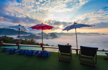 Big colorful umbrellas at terrace have mountain view with sea of fog on the morning and sunrise view.