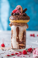 Chocolate indulgent frosting exreme milkshake with donut  and sweets. Crazy freakshake food trend....