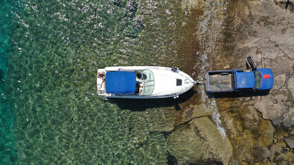 Aerial top view photo of inflatable speed boat on trailer being towed by truck from emerald exotic sea to land