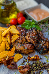 Delicious piece of meat served with potatoes decorated with dry tomatoes, pepper and herbs