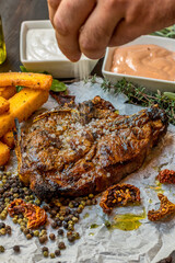 Delicious piece of meat served with potatoes decorated with dry tomatoes, pepper and herbs