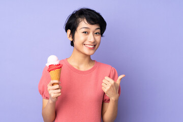 Young Vietnamese woman with short hair holding a cornet ice cream over isolated purple background with thumbs up because something good has happened