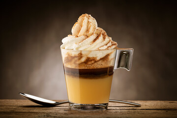 Cup of coffee with whipped cream, caramel cream, and cinnamon powder.