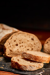 Freshly made integral black domestic bread on black stone cutting board. Very shallow depth of field
