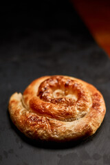 Freshly made pastry burek on black stone cutting board. Very shallow depth of field