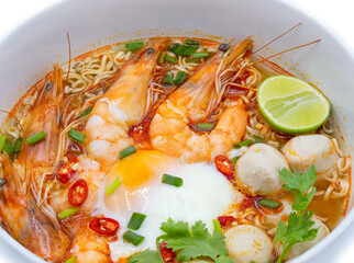 Tom yum kung or hot and spicy shrimp soup boiled with noodle and ingredient inside, in the white bowl.