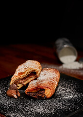 Freshly made chopped pastry with chocolate on black stone cutting board. Very shallow depth of field
