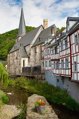 Fototapeta na wymiar Rural scene with half-timbered houses and an old church beside a creek in a typical ancient German village