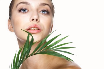 Clean skin cosmetology beautiful female face and green leaves