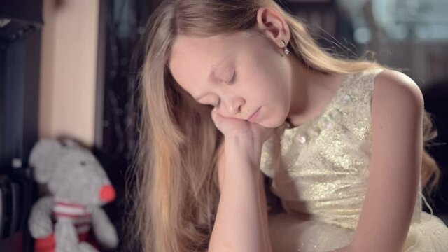 A sad little girl in a pink dress lonely looks at his stuffed toy. Spoiled holiday. A brooding child
