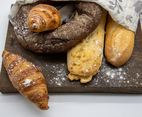 Several types of bread lie on a rough wooden Board on light background.