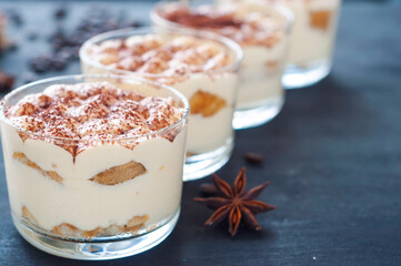 exquisite tiramisu in glasses decorated with cocoa powder on a dark background