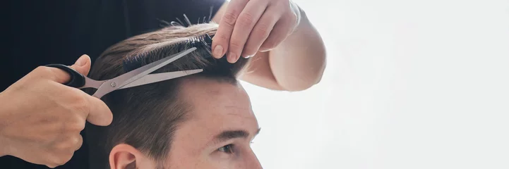 Fotobehang Kapsalon man with a beard cuts and cares for the hair himself in a quarantine coronavirus pandemic covid 19, the concept of stay home, a home hairdresser  © shintartanya