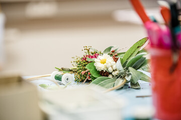 Florist at work: woman making rose hip and hawthorn wreath