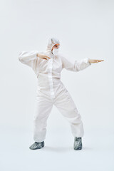 Full lenght portrait of happy dancing doctor in PPE suit on blue background