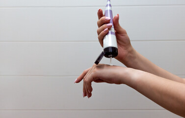Close up of well-groomed female hands with a tube of cosmetic on the white tile background. Skincare and handcare concept. Cosmetic procedure.