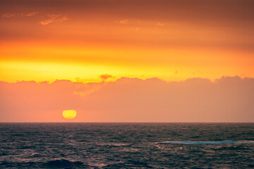 Big yellow sun falling behind the sea at Christies Beach during sunset time, South Australia