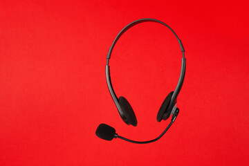 Online technical support service. Call center, helpline. Headphones with microphone on red background.
