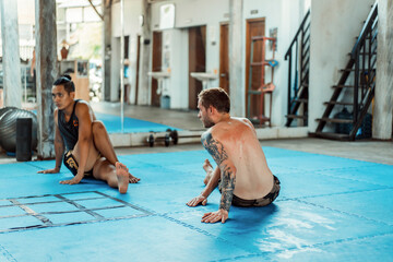 Training in the gym in the ring with a muay thai trainer. Tattooed caucasian man and Asian trainer....