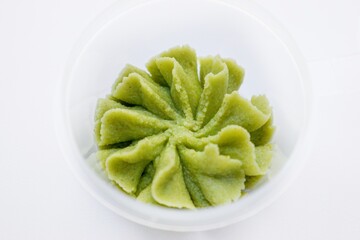 A portion of green spicy wasabi spice on a white background.