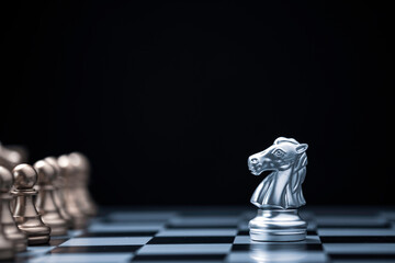 Silver horse chess encounters with gold chess enemy on chess board and black background. Market or business competitor concept.