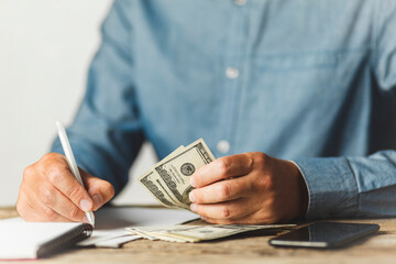 Businessman is counting dollars, accumulating (saving) money. Income growth, salary increase. Deductions for retirement.