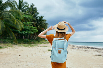 Woman tourist blue backpack walking on sandy beach island Exotic palm trees