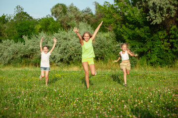 Obraz premium Kids, children running on meadow in summer's sunlight. Look happy, cheerful with sincere bright emotions. Cute caucasian boys and girls. Concept of childhood, happiness, movement, family and summer.