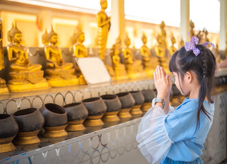 Girl paying respect to buddha statue.