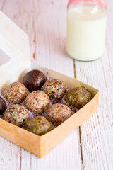 Healthy snack. Energy ball with date plum, black and white sesame, chia and currant in paper box on wooden table. Vegan vegetarian.