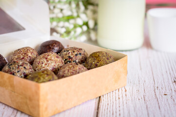 Healthy snack. Energy ball with date plum, black and white sesame, chia and currant in paper box on wooden table. Vegan vegetarian.