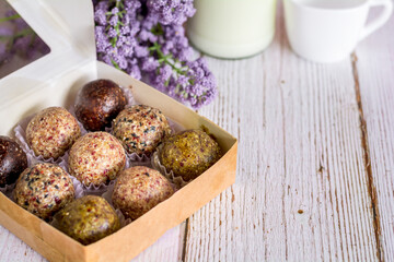 Healthy snack. Energy ball with date plum, black and white sesame, chia and currant in paper box on wooden table. Vegan vegetarian.