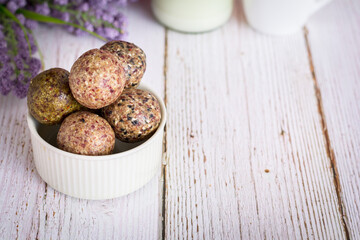 Healthy snack. Energy ball with date plum, black and white sesame, chia and currant in ceramic bowl on wooden table. Vegan vegetarian.