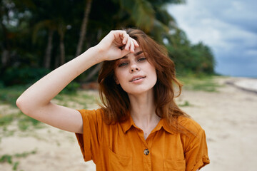 woman tourist holds hand near face on background of island with palm trees
