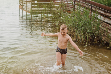 Boy playing in the water on a lake shore. Summer Holidays