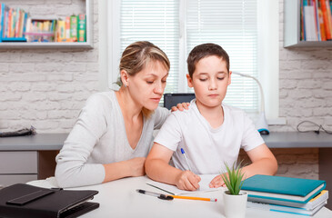 Mother helps son to do lessons. Home schooling and distance learning