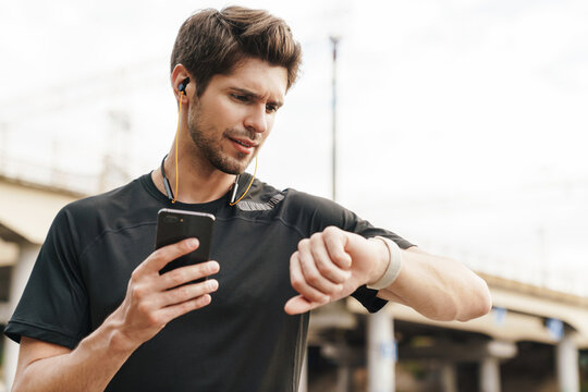 Image of sportsman using cellphone and smartwatch while working out