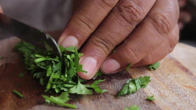 Closeup shot of hand chopping coriander 