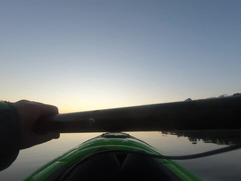 Girl kayaking through the lake on a calm summer morning