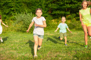 Obraz premium Kids, children running on meadow in summer's sunlight. Look happy, cheerful with sincere bright emotions. Cute caucasian boys and girls. Concept of childhood, happiness, movement, family and summer.