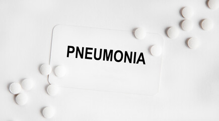 On a white business card there is an inscription pneumonia, next to a pills. White background.
